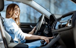 Smiling woman driving a car while adjusting the AC