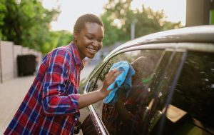 Woman cleaning exterior car window with a cloth